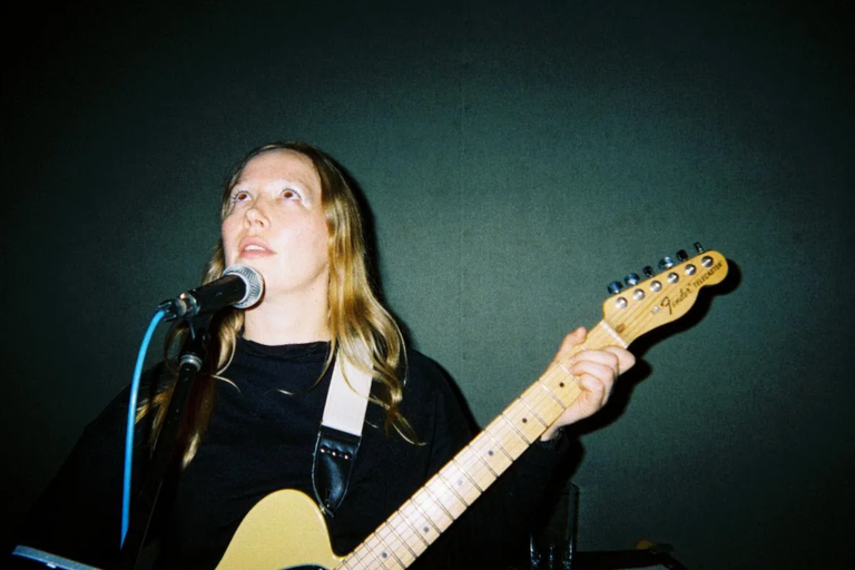 Australian singer-songwriter Julia Jacklin playing a Fender Telecaster electric guitar while singing live into a microphone.